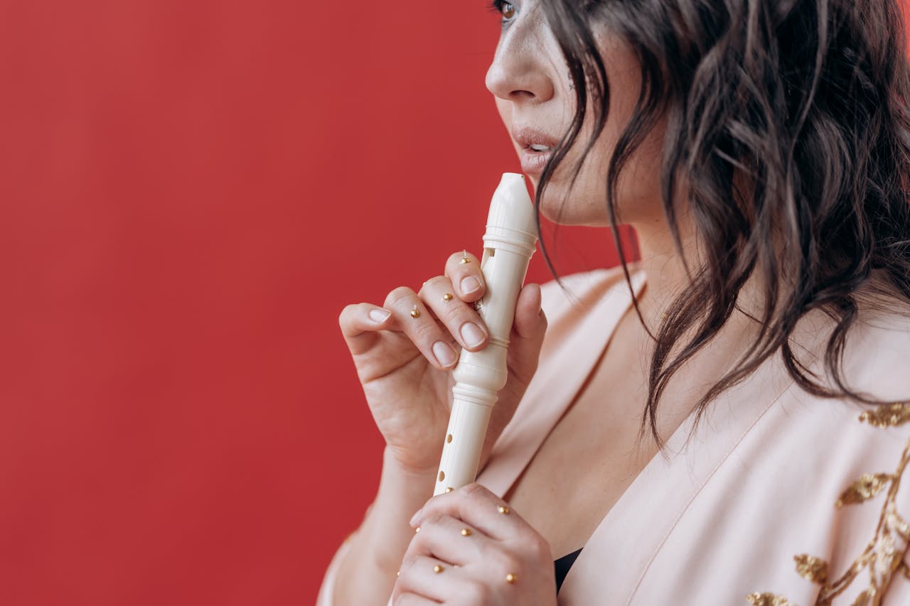 Close-up of a woman holding a recorder with a red backdrop, depicting a musical theme.